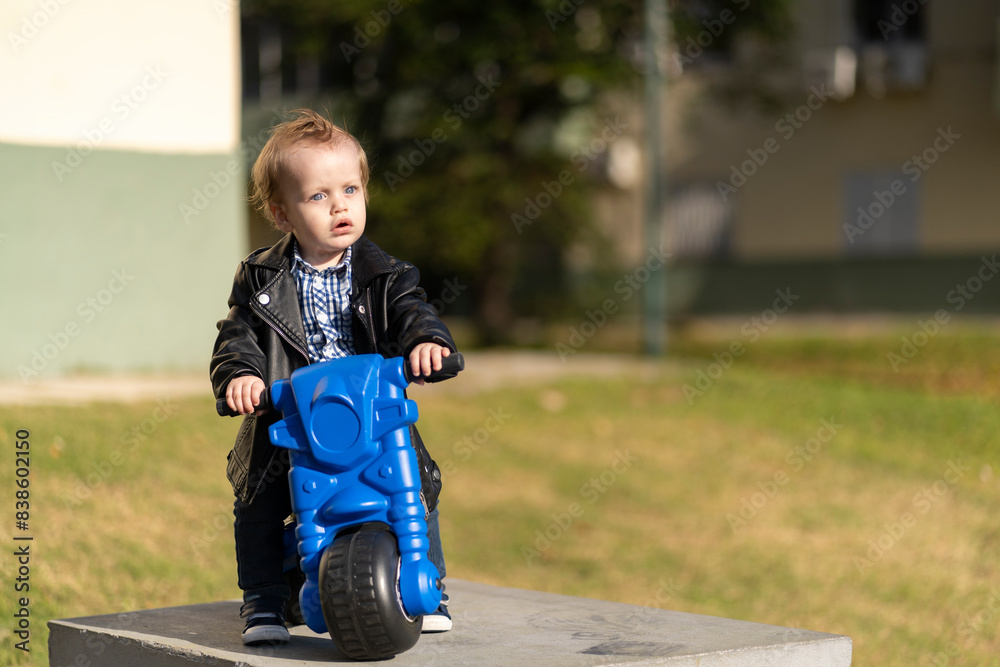 One year old blonde and blue eyes baby riding a motorcycle in the park One year old blonde and blue eyes baby riding a motorcycle in the park