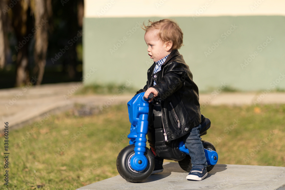 One year old blonde and blue eyes baby riding a motorcycle in the park One year old blonde and blue eyes baby riding a motorcycle in the park