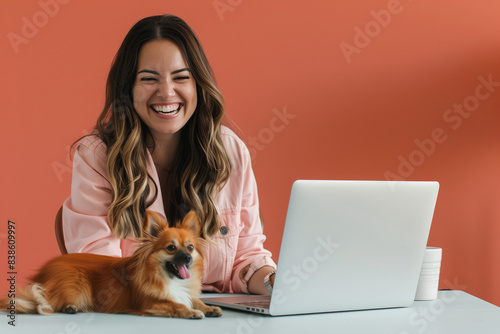 Happy White Woman Working on Laptop with Small Dog in Bright and Colorful Home Office © Sage Studios