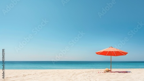 Orange umbrella on sandy beach with clear blue sky