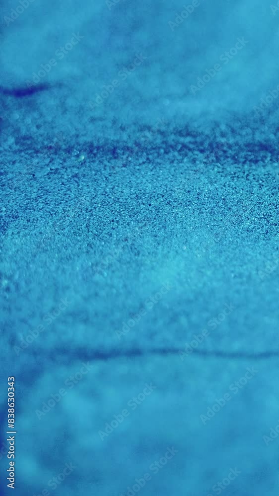 Vertical video. Glitter paint. Ink splash. Defocused blue color sparkling particles texture liquid emulsion flow motion glamour abstract background. Vertical video. Glitter paint. Ink splash. Defocused blue color sparkling particles texture liquid emulsion flow motion glamour abstract background.