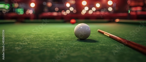 Close-up view of a pool table with a cue stick and ball in focus, creating a perfect atmosphere for a night out at the bar.