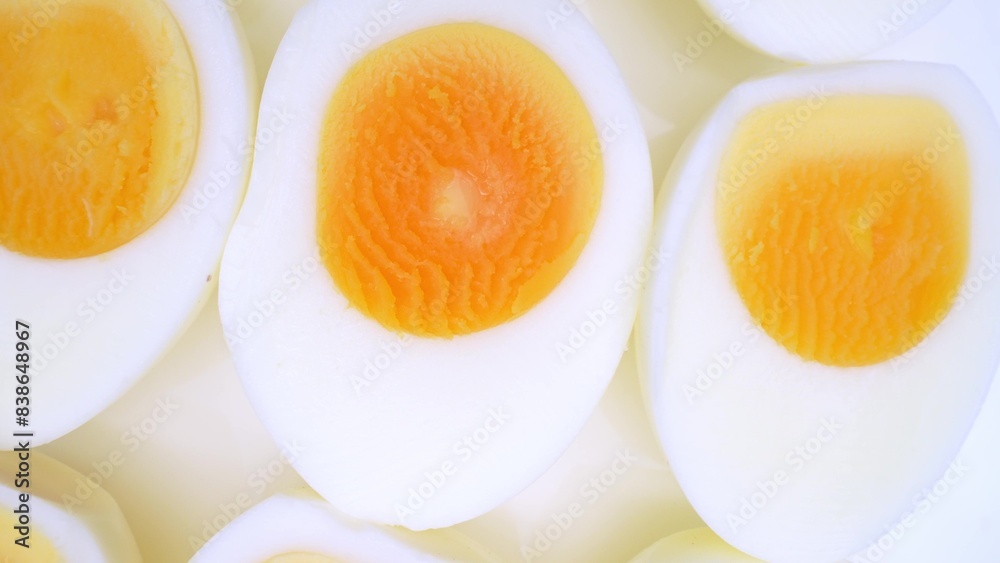 Sliced boiled eggs arranged elegantly, revealing their immaculate whites enveloping velvety, golden yolks. The yolks exude richness against the backdrop of the smooth, tender egg whites.
Sliced boiled eggs arranged elegantly, revealing their immaculate whites enveloping velvety, golden yolks. The yolks exude richness against the backdrop of the smooth, tender egg whites.