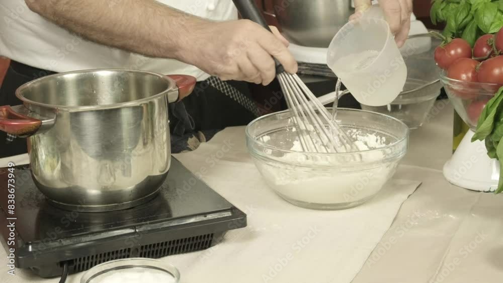 Closeup hands of chef add water to flour mixture Italian kitchen, tomatoes basil Closeup hands of chef add water to flour mixture Italian kitchen, tomatoes basil