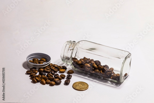 Bild auf Leinwand Roasted coffee beans on a white background with a coin implying the concept of coffee trade and business in prefect details