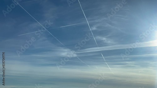 Aerial view of some jet contrails in a bright and sunny sky shot from another airplane flying bellow. 4K 60FPS photo