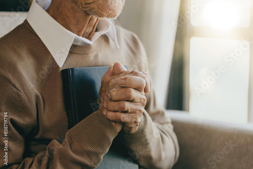 Old man Pray for god blessing to wishing to have a better life. hands praying to god with the bible light from the window, begging for forgiveness and believing in goodness. Christian prayer to god.