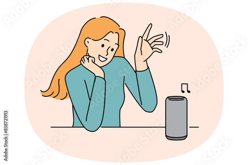 Woman uses wireless speaker with voice control to listen to music or communicate with virtual interlocutor. Wireless speaker for smart home and IOT technology near young smiling girl
