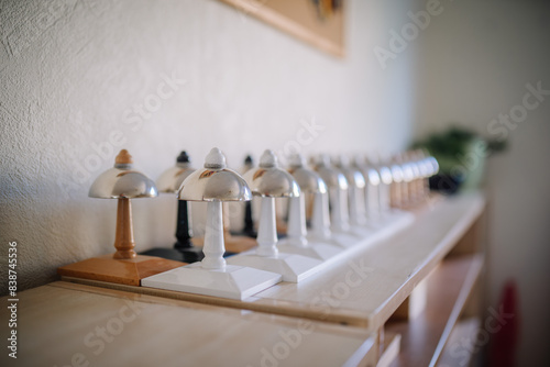 Valmiera, Latvia - May, 22, 2024 - A row of Montessori bells lined up on a shelf in a classroom, each bell with a unique color and design. The background is blurred. photo