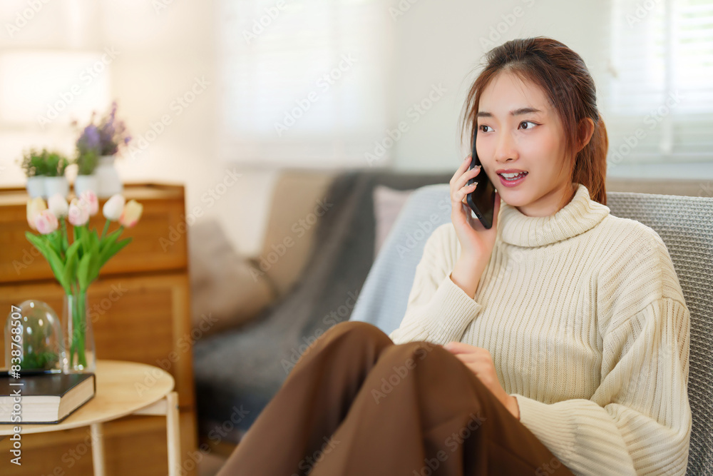 Young asian women in sweater using smartphone to talking and meeting for communication while sitting on the couch to relaxation and doing activity for spending time with slow life lifestyle at home Young asian women in sweater using smartphone to talking and meeting for communication while sitting on the couch to relaxation and doing activity for spending time with slow life lifestyle at home