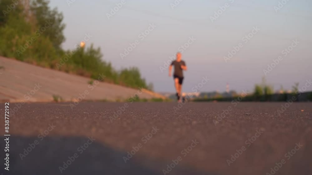 guy in training runs at the camera out of focus, the sports background is blurred. young athlete performs exercises at full strength on his own. outdoor physical education in the city. guy in training runs at the camera out of focus, the sports background is blurred. young athlete performs exercises at full strength on his own. outdoor physical education in the city.