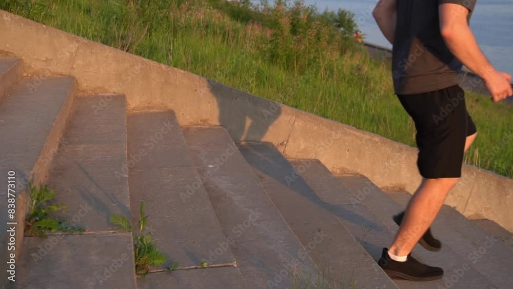 sportsman goes down the steps of a concrete staircase. men's legs in black shorts and sneakers. warm-up, preparation for running training. sportsman goes down the steps of a concrete staircase. men's legs in black shorts and sneakers. warm-up, preparation for running training.