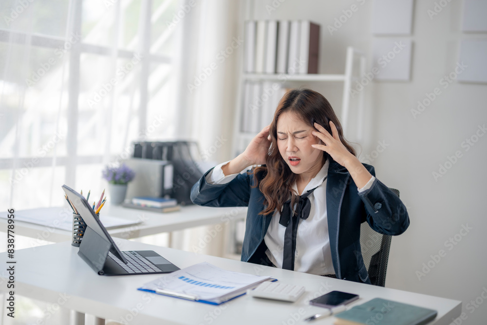 A woman in a business suit is sitting at a desk with a laptop A woman in a business suit is sitting at a desk with a laptop