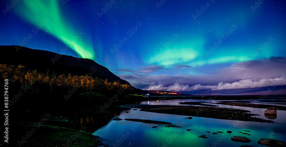 Northern lights dancing over calm lake in Abisko national park in north of Sweden.