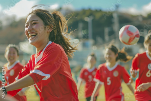 A team of Japanese women footballers soccer happily compete in a lighthearted scrimmage, each aiming to maneuver the ball with finesse and accuracy.