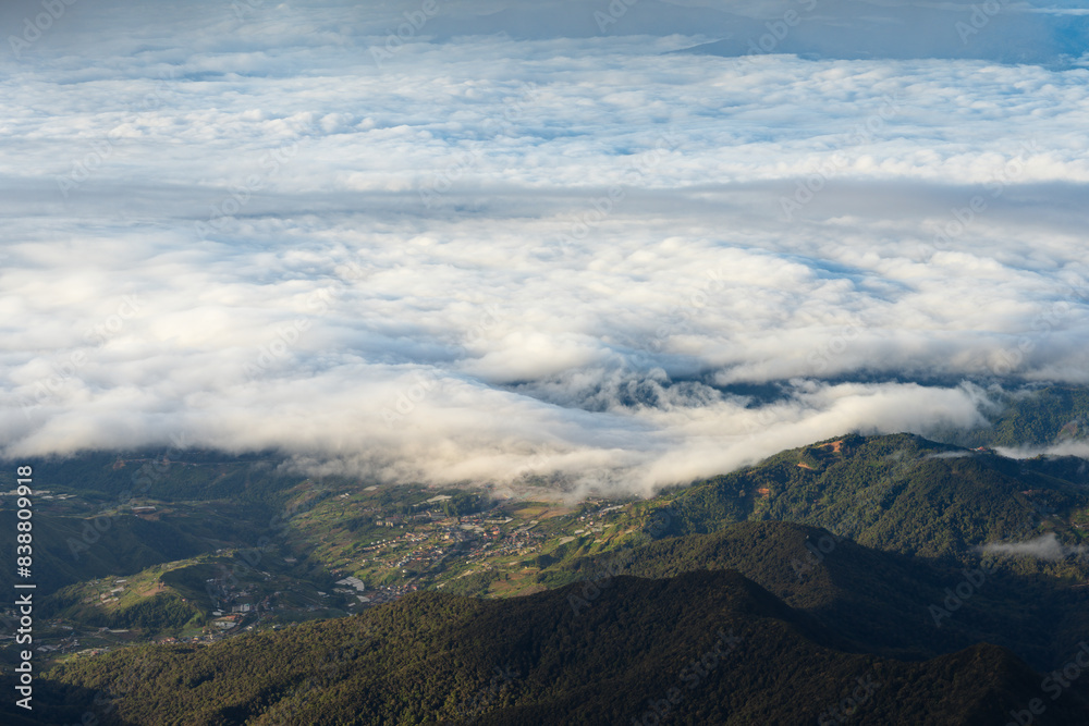 clouds cover the mountains and hills below the ocean and town clouds cover the mountains and hills below the ocean and town