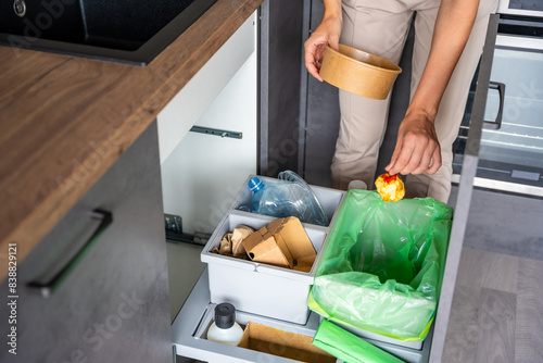 Obraz na plátně Woman throwing trash into household bins for waste sorting in the kitchen for recycle
