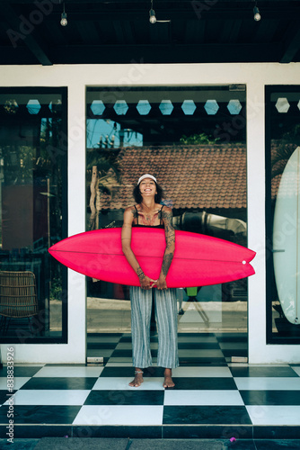 Portrait of young happy stylish woman with surfboard.