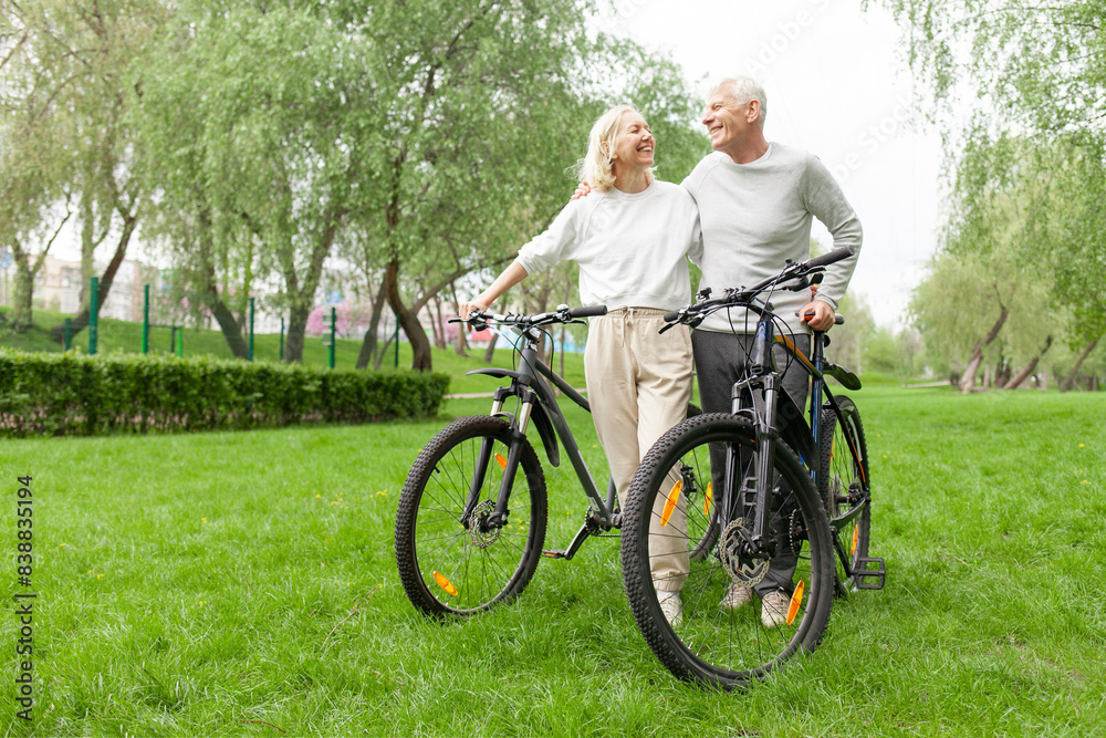 elderly senior couple rides bicycle in the park in the summer and smiles, old gray-haired man and woman are actively resting outdoors, old people practice cycling in forest elderly senior couple rides bicycle in the park in the summer and smiles, old gray-haired man and woman are actively resting outdoors, old people practice cycling in forest