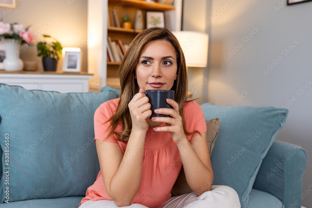 Young happy relaxed Latin woman enjoying quiet moments at home with cup of tea or coffee, smiling female holding mug with hot drink resting on sofa in living room and dreaming, relaxing of everything Young happy relaxed Latin woman enjoying quiet moments at home with cup of tea or coffee, smiling female holding mug with hot drink resting on sofa in living room and dreaming, relaxing of everything