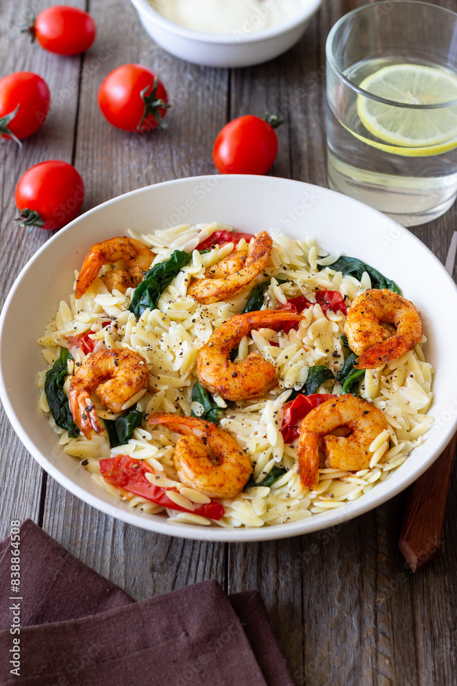 Orzo pasta with shrimp, spinach and tomatoes. Italian Cuisine. Seafood.