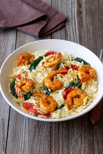 Orzo pasta with shrimp, spinach and tomatoes. Italian Cuisine. Seafood.
