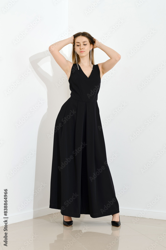Stylish young woman in a long black dress with a low neckline threw her arms behind her head Stylish young woman in a long black dress with a low neckline threw her arms behind her head