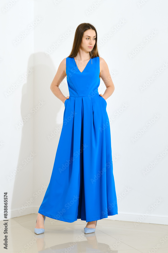 Stylish trendy woman in blue long sleeveless dress holding her hands in pockets Stylish trendy woman in blue long sleeveless dress holding her hands in pockets