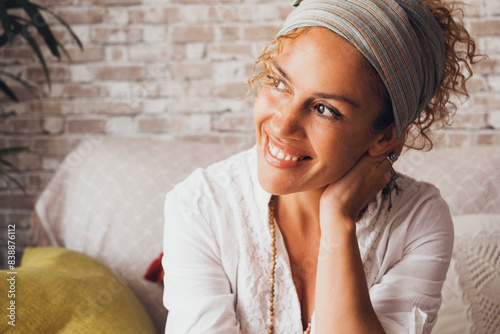 Canvas Print Happy curly woman sitting on sofa at home smiling happily