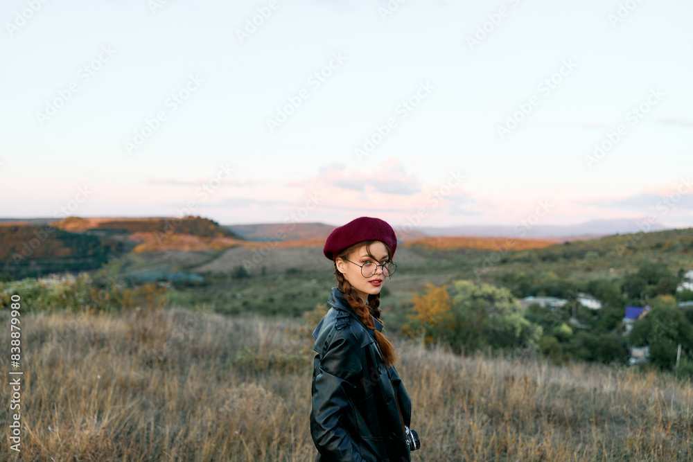 Stylish woman in red beret and leather jacket standing confidently in an open field Stylish woman in red beret and leather jacket standing confidently in an open field