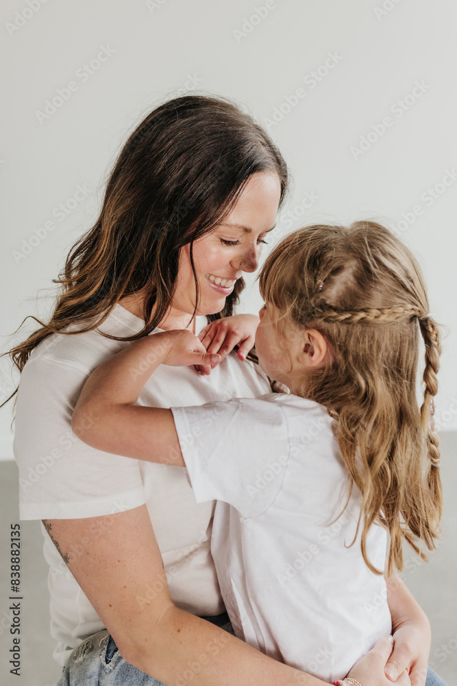Mother and daughter snuggle together while looking at each other Mother and daughter snuggle together while looking at each other