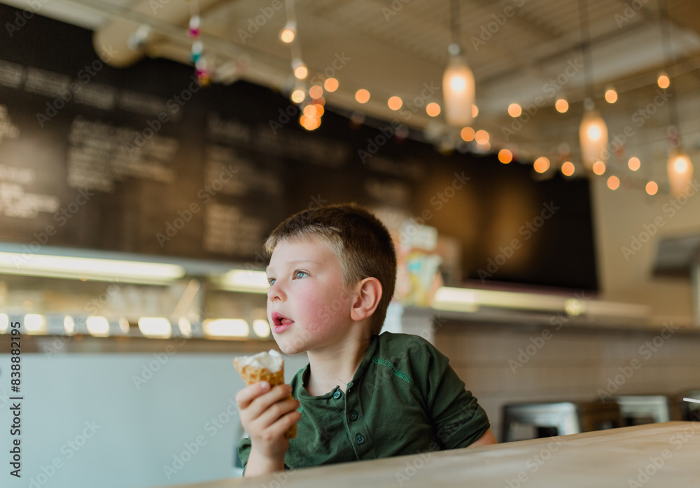 Young boy enjoying an ice cream cone inside a cozy ice cream shop Young boy enjoying an ice cream cone inside a cozy ice cream shop
