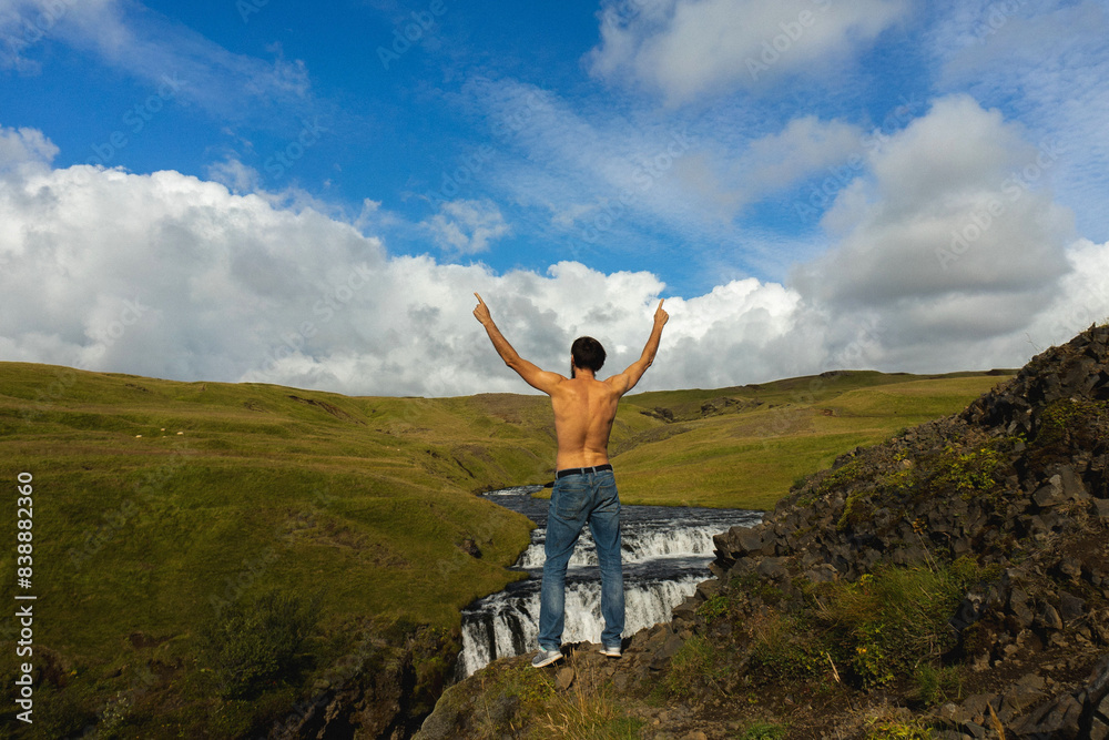 Man standing above beautiful waterfall at Iceland.