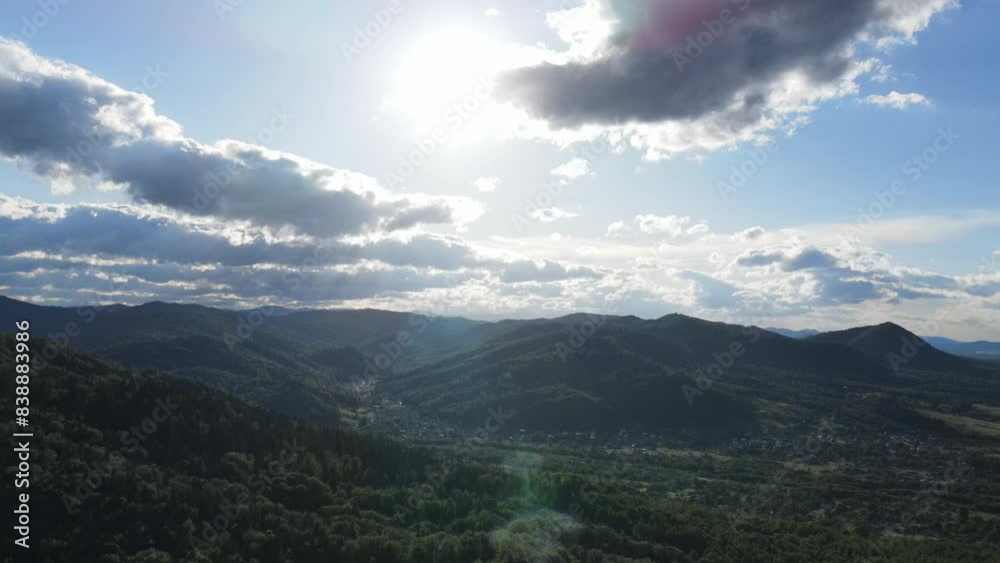 Aerial view of idyllic rolling hills landscape in Carpathians with houses, fields and amazing mountains in sunny light at warm summertime Aerial view of idyllic rolling hills landscape in Carpathians with houses, fields and amazing mountains in sunny light at warm summertime