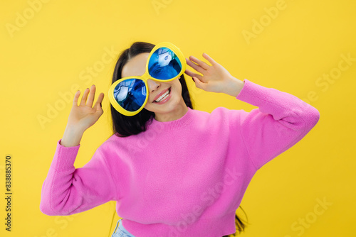 Stunning female model in huge sunglasses posing with smile on yellow background