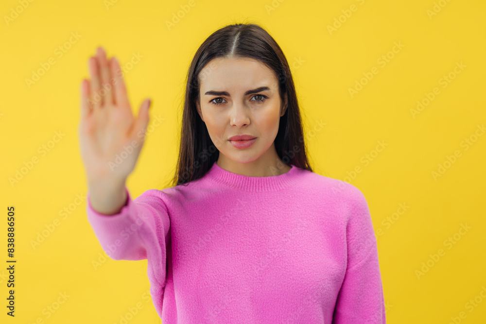 serious young woman standing with outstretched hand showing stop gesture isolated over yellow background serious young woman standing with outstretched hand showing stop gesture isolated over yellow background