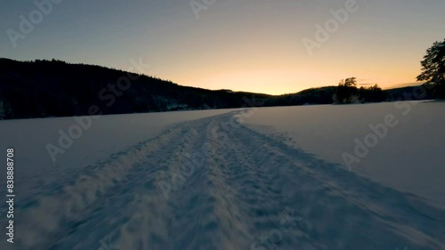 Snow-covered tracks are leading through a serene, snowy landscape at dawn. photo