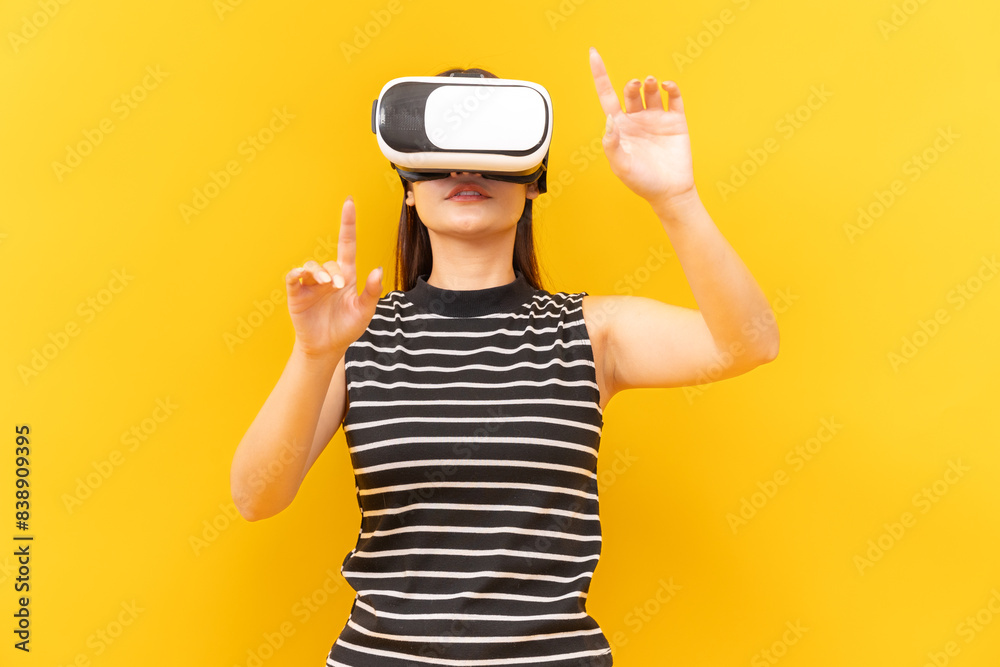 Asian young woman playing video games using mobile with headphones on yellow background isolated. Asian young woman playing video games using mobile with headphones on yellow background isolated.