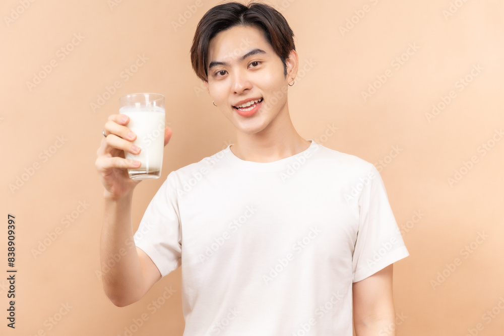 A happy asian people in white shirts, holding glasses of milk and a bowl of salad, against a beige background. A happy asian people in white shirts, holding glasses of milk and a bowl of salad, against a beige background.