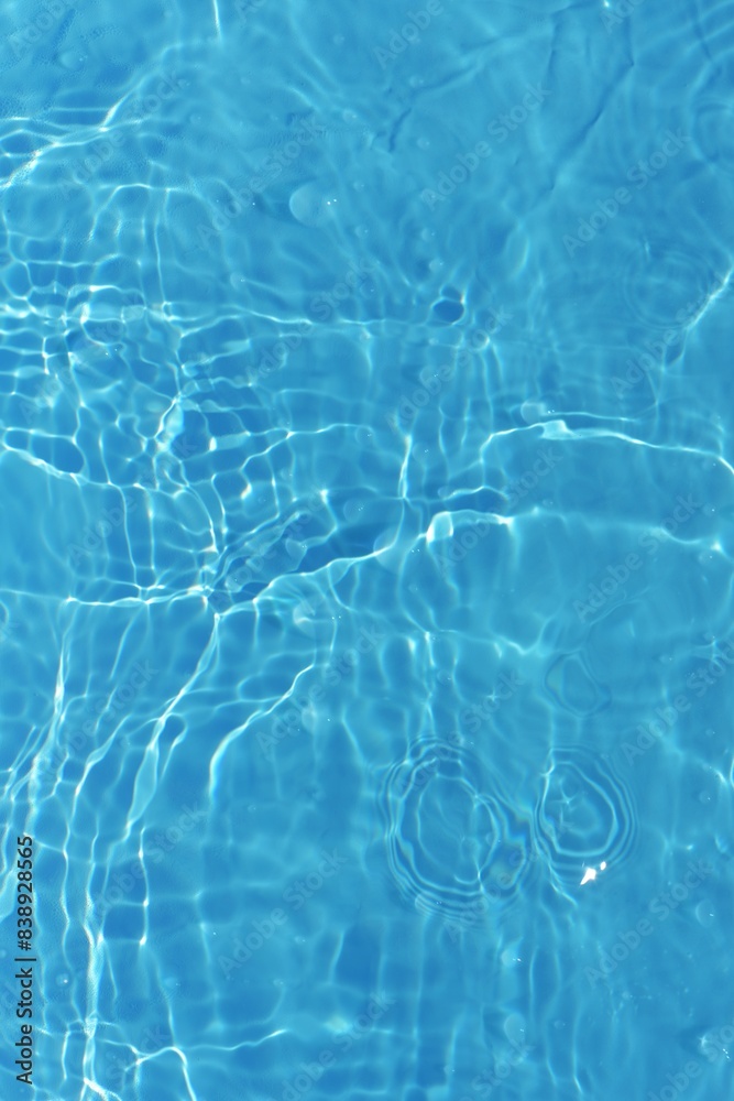 Obraz premium Blue water with ripples on the surface. Defocus blurred transparent blue colored clear calm water surface texture with splashes and bubbles. Water waves with shining pattern texture background. 