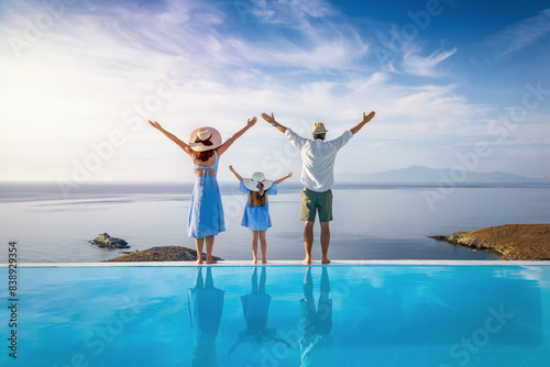 Photography A happy family on summer holidays stands by the swimming pool and enjoys the bea