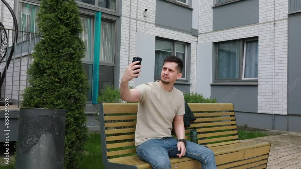 Man Sitting on Bench Holding Cell Phone Man Sitting on Bench Holding Cell Phone