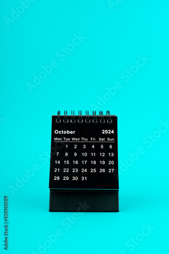 Black Calendar for October 2024. Desktop calendar on a green background.