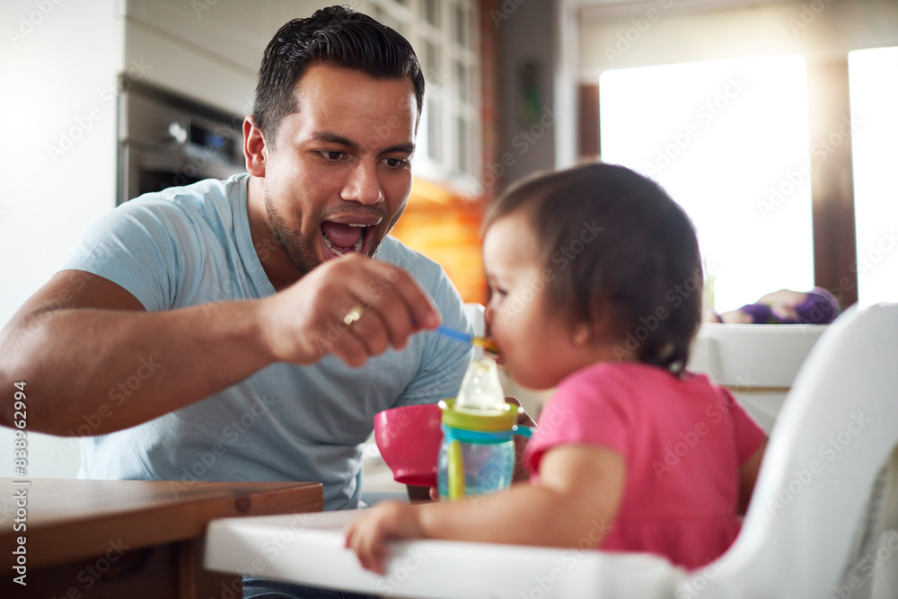 Father feeding baby girl sitting in high chair at home Father feeding baby girl sitting in high chair at home