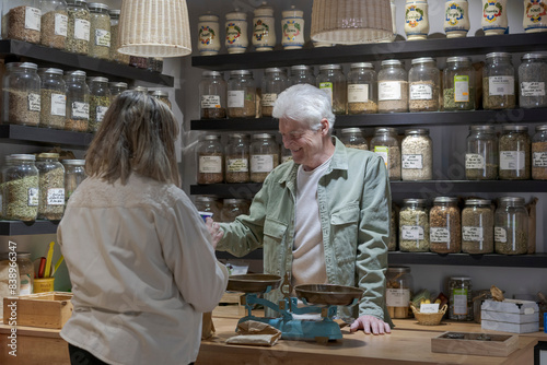 Smiling senior man with customer behind the counter in his shop