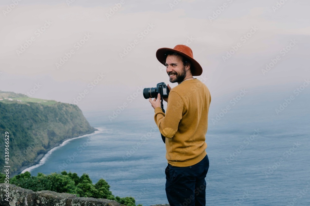 Obraz premium Smiling man with a camera at the coast on Sao Miguel Island, Azores, Portugal