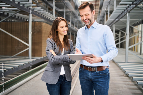 Smiling businesswoman and businessman using tablet in a factory