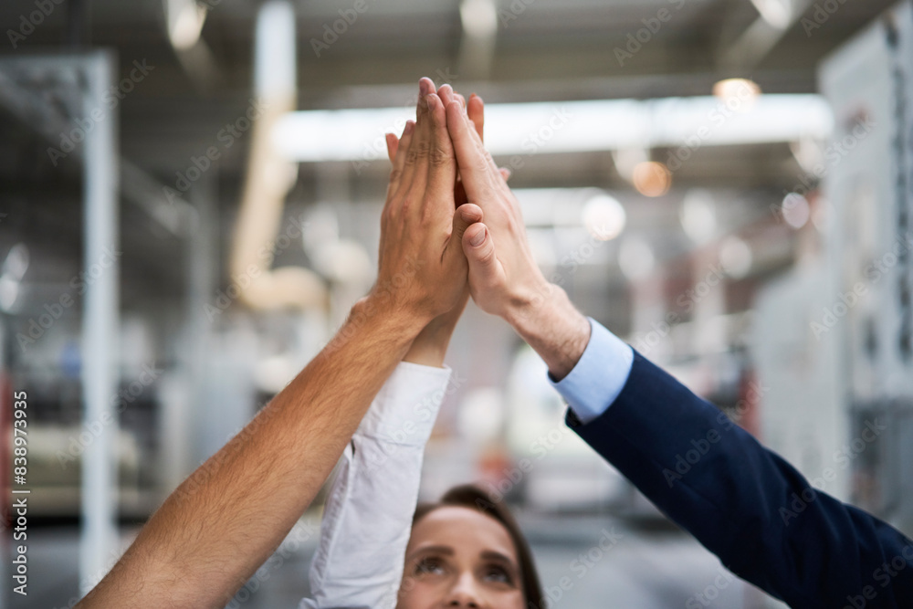 Close-upof businessman and employees high fiving in a factory Close-upof businessman and employees high fiving in a factory