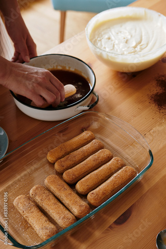 Woman's hand dipping ladyfingers in coffee photo