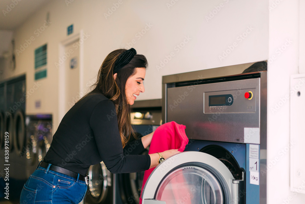 Young woman doing the laundry in a launderette